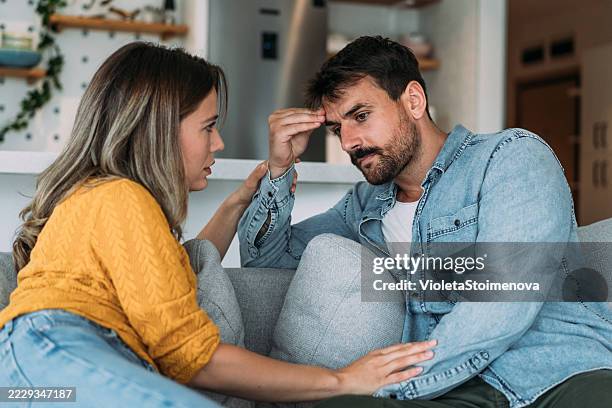 worried couple talking together in the living room at home. - mid adult stock pictures, royalty-free photos & images