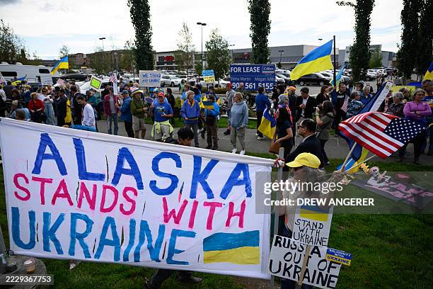 Demonstrators wave flags and hold a banner as they rally in support of Ukraine along Seward Highway in Anchorage, Alaska, on August 14 on the eve of...