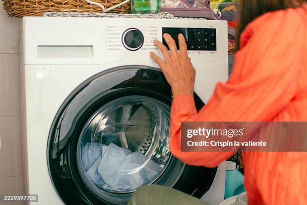 woman using washing machine, doing laundry at home - washing machine stock pictures, royalty-free photos & images