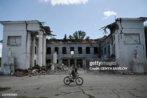 Man rides his bicycle past a destroyed building in Druzhkivka, Donetsk region, on August 15 amid the Russian invasion of Ukraine. Local authorities...