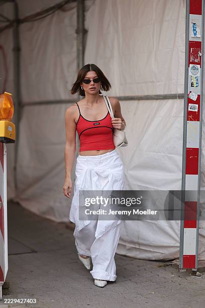Sophia Geiss is seen wearing oval rimless black sunglasses from Vehla Eyewear, chunky silver hoop earrings, a silver nose ring, a fitted red...