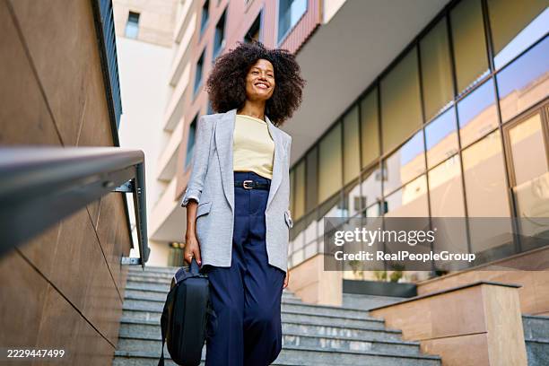 smiling businesswoman climbing stairs in the city - black blazer stock pictures, royalty-free photos & images