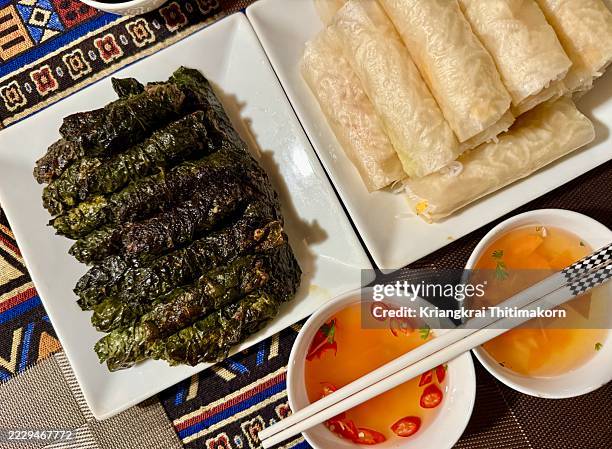 eating bò nướng lá lốt (grilled beef in lolot leaf) and fresh spring rolls. - vietnamese cuisine stock pictures, royalty-free photos & images