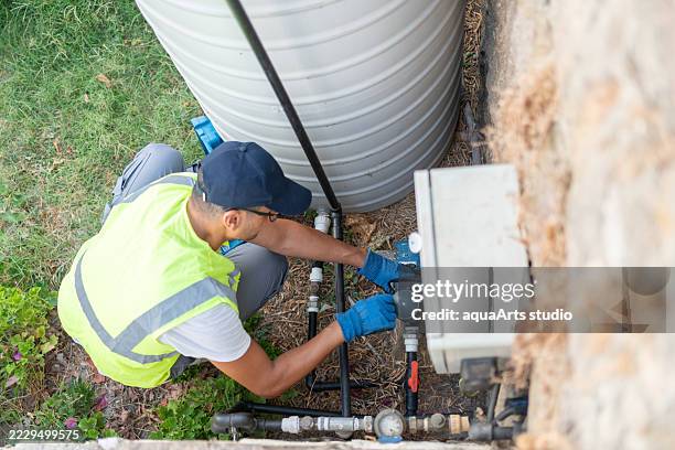 klempner, der den wasserpumpenmotor des wasserspeichers repariert - wasserpumpanlage stock-fotos und bilder