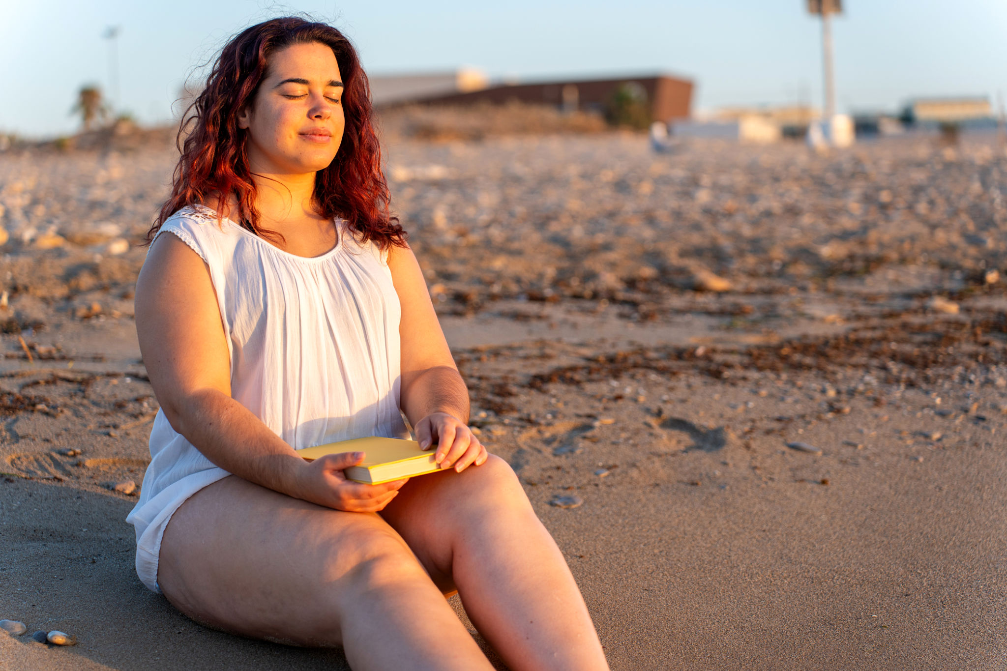 Curvy woman breathing and relaxing on the beach at sunset Curvy woman breathing and relaxing on the beach at sunset