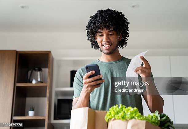 man checking the receipt after arriving home with the groceries - grocery receipt stock pictures, royalty-free photos & images