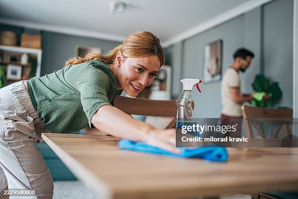 couple cleaning dining table together in modern apartment - housework stock pictures, royalty-free photos & images