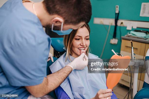 dentist showing teeth whitening shades to patient in dental clinic - implante dentário imagens e fotografias de stock
