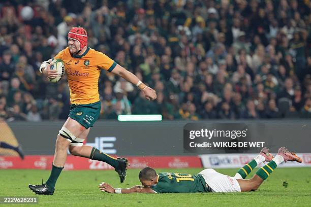 Australia's number eight Harry Wilson runs with the ball to score a try as South Africa's fly-half Manie Libbok misses a tackle during the Rugby...