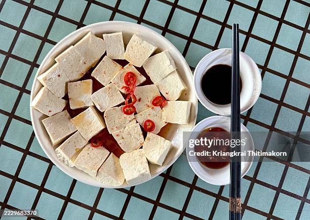 a plate of tofu with a sauce and garnished with chili slices. - tofu stock pictures, royalty-free photos & images