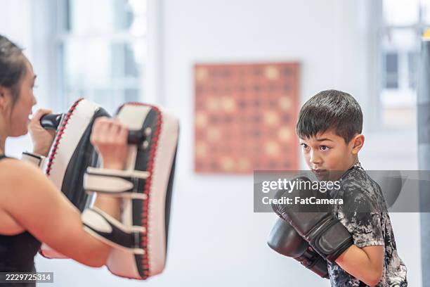 focused boy practicing boxing techniques with a skilled trainer in a gym setting - boxing class stock pictures, royalty-free photos & images