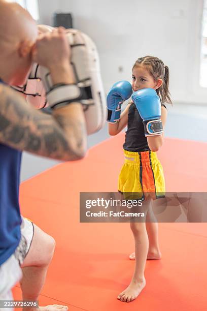 young girl learning boxing techniques in a martial arts training session - martial arts stock pictures, royalty-free photos & images