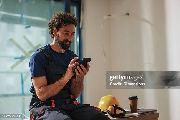 construction worker using smartphone during break on construction site - builder phone stock pictures, royalty-free photos & images