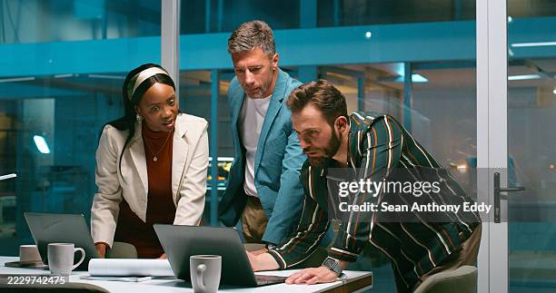 people, reading and laptop in office at night for planning, article feedback and press release. staff, team and proofreading for media, explain headline idea and brainstorming of publication deadline - journalist stock pictures, royalty-free photos & images