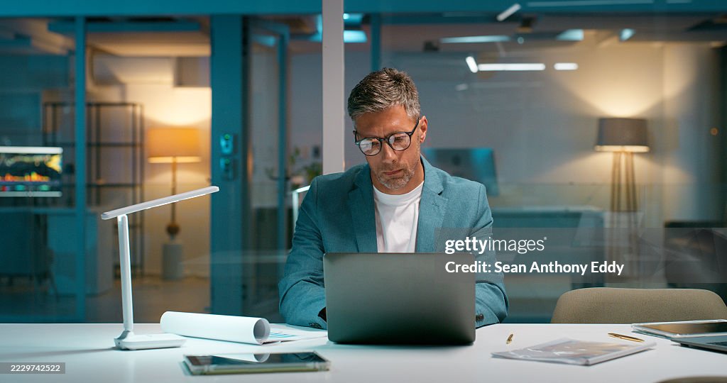 Broker, Lektüre und Laptop mit Geschäftsmann im Büro für Handelsbericht, Nacht und Investitionsplan. Research, Börsenanalyse und Account Manager mit reifer Person für Überstunden und Portfolio