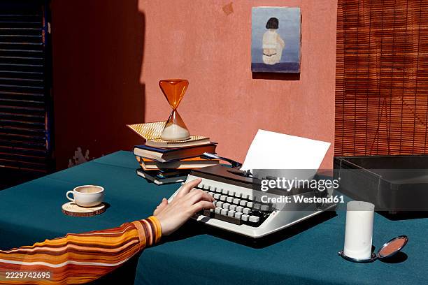 a nostalgic workspace with a mechanical typewriter and hourglass on a desk - typewriter desk stock pictures, royalty-free photos & images