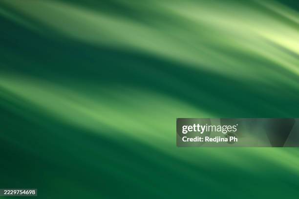 abstract green light beams creating a smooth and flowing texture pattern - flouté photos et images de collection