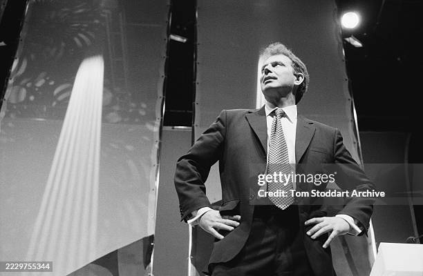 Low-angle view of British politician Tony Blair, wearing a dark blazer over a white shirt and a checked tie, his hand on his hips, during the Labour...