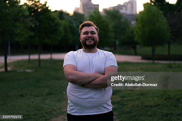 retrato de un hombre sonriente con sobrepeso que comienza a hacer ejercicio en el parque de la ciudad - obesidad fotografías e imágenes de stock