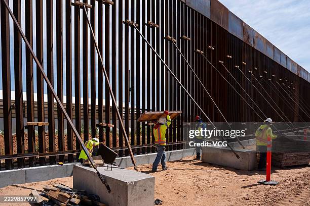 Workers work at the construction site of a new 'secondary' wall along the U.S.-Mexico border to reinforce the existing steel fence on August 12, 2025...