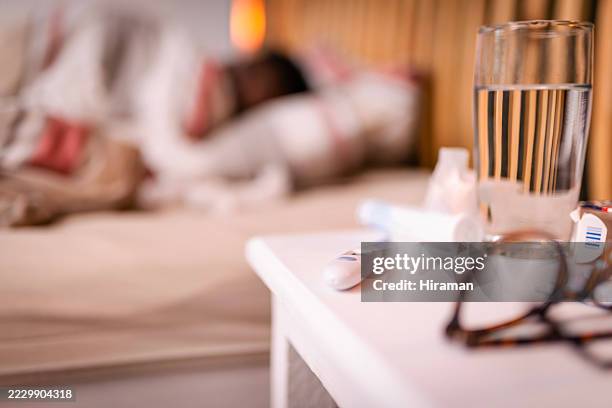 glass of water and thermometer on nightstand near resting person - side table stock pictures, royalty-free photos & images
