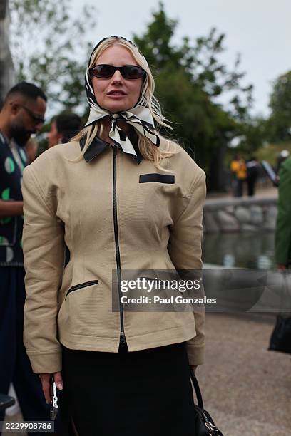 Guest is seen wearing a beige barn jacket with a silk head scarf at the MKDT Studio show. During Copenhagen Fashion Week day three on August 06, 2025...