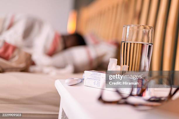 close-up of bedside items and sick person resting in a cozy bedroom - night table stock pictures, royalty-free photos & images
