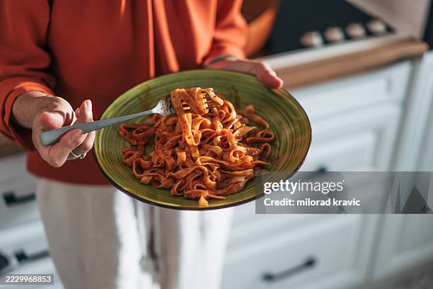 mujer sosteniendo plato de deliciosos tallarines con salsa de tomate - carbohidrato fotografías e imágenes de stock