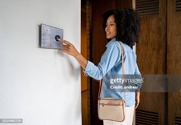 femme quittant sa maison intelligente et verrouillant la porte à l’aide d’une application mobile - domotique photos et images de collection