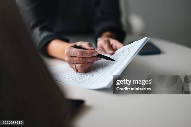 close-up of a person reviewing and discussing document in office environment - documenten archiveren stockfoto's en -beelden