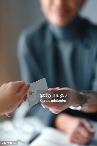 business transaction featuring credit card exchange in a modern office setting - handing over credit card stock pictures, royalty-free photos & images