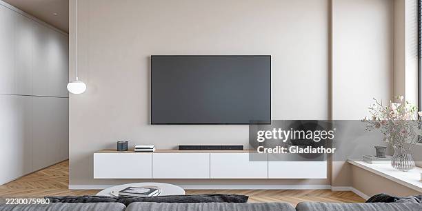 a modern minimalistic living room with a lcd screen on empty beige wall with copy space, a low white cabinet, coffee table, gray sofa, windows and decoration, a hallway - tela de projecção imagens e fotografias de stock