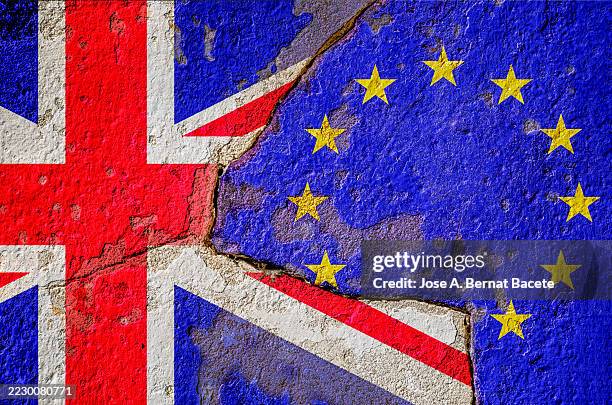 flags of the european union and the united kingdom on an old wall separated by a deep crack. - brexit stockfoto's en -beelden
