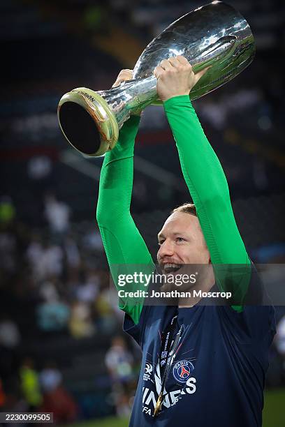 Matvei Safonov of PSG celebrates with the trophy in front of fans following the penalty shoot out victory in the UEFA Super Cup 2025 match between...