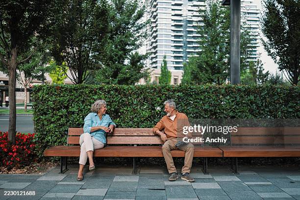 strangers starting conversation on park bench - stranger stock pictures, royalty-free photos & images