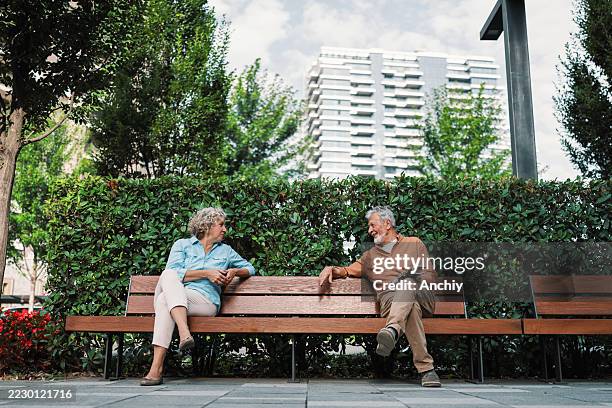 strangers starting conversation on park bench - park bench stock pictures, royalty-free photos & images