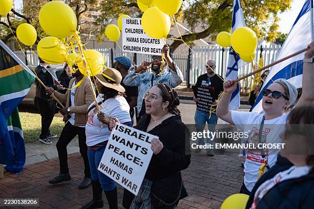 Supporters sing and hold placards at a pro-Israel demonstration outside the Red Cross headquarters calling to "Bring the Hostages Home" with former...