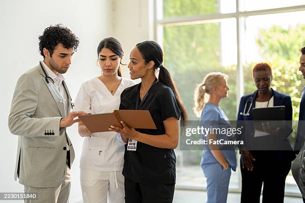 diverse medical team collaborating in a bright hospital environment - wereldwijde gezondheid stockfoto's en -beelden