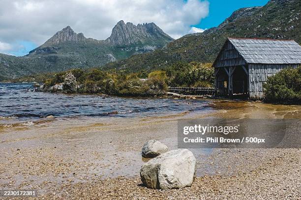 scenic view of dove lake and cradle mountain with a rustic boatshed,west coast,australia - cradle mountain stock pictures, royalty-free photos & images