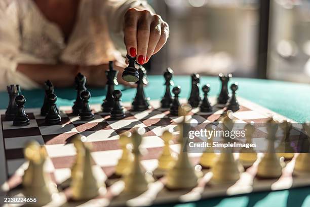 a woman starts a chess game with the first move of a pawn - schach stock-fotos und bilder