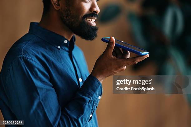 man speaking into smartphone for communication with voice recognition technology - dictation stock pictures, royalty-free photos & images