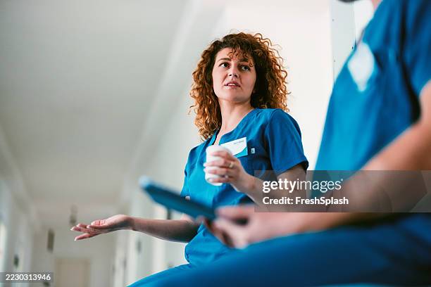 healthcare professionals in discussion within a bright medical facility hallway - nursing assistant stock pictures, royalty-free photos & images