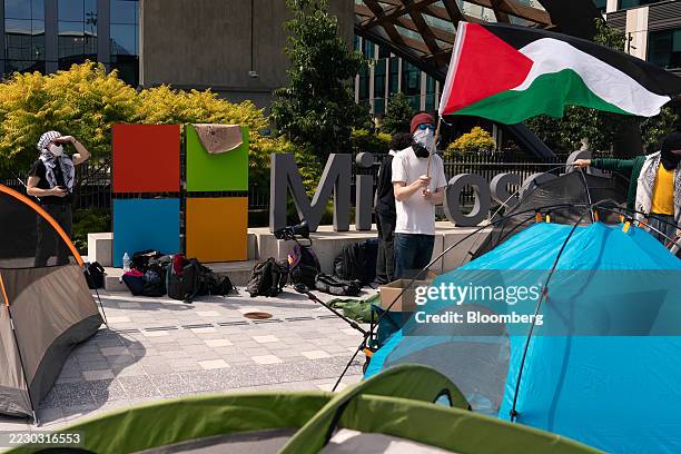 Demonstrator holds a Palestinian flag near tents during a protest at the Microsoft Campus in Redmond, Washington, US, on Tuesday, Aug. 19, 2025....