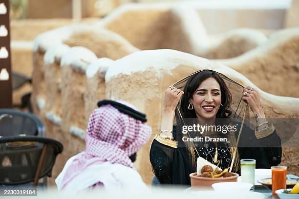 restaurant sur le toit avec diverses personnes profitant d’un repas, avec des vêtements et une architecture traditionnels du moyen-orient. - culture saoudienne photos et images de collection