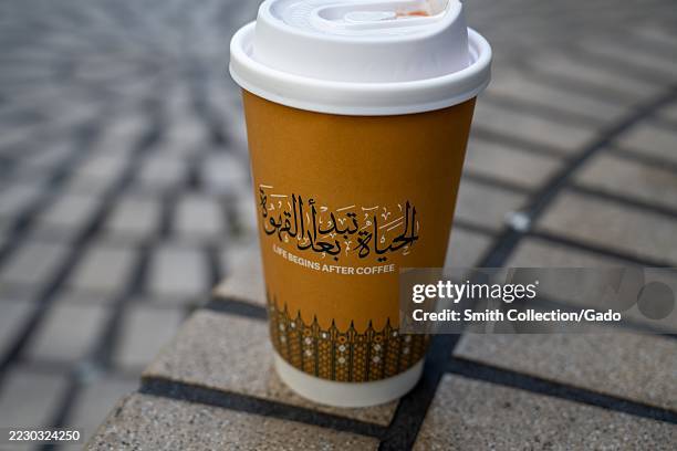 Takeaway Delah Coffee cup with Arabic script and Life Begins After Coffee slogan on patterned pavement, San Francisco, California, August 14, 2025.