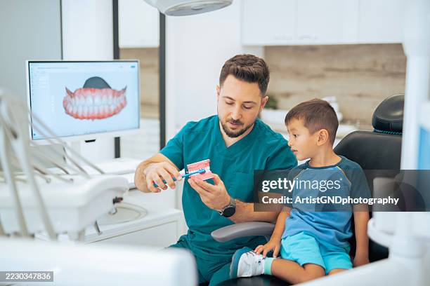 dentist showing a small asian boy the habit of dental hygiene. - philippine childrens medical center stock pictures, royalty-free photos & images