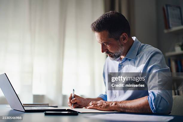 professional businessman working in a modern home office on a laptop - coordinator stock pictures, royalty-free photos & images