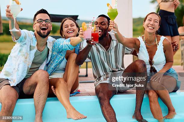friends toasting cocktails at poolside party, enjoying summer vacation - city break stock pictures, royalty-free photos & images