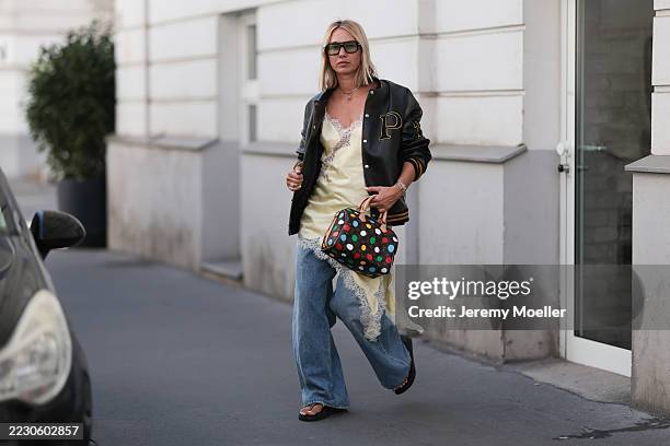 Karin Teigl seen wearing Kuboraum oversized square black sunglasses with tinted green lenses, Prada black varsity oversized bomber jacket featuring...