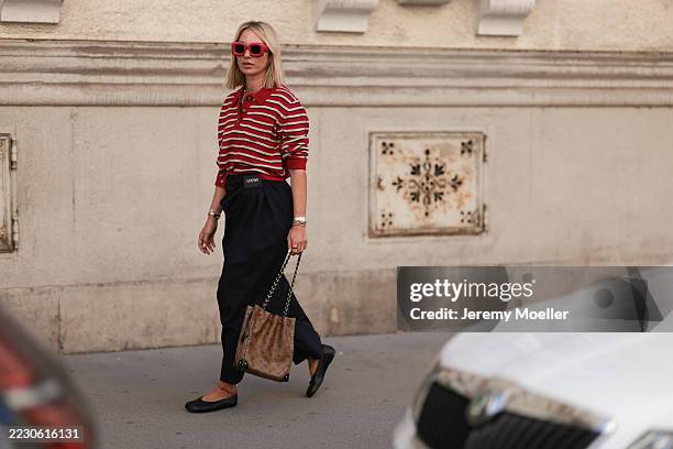 Karin Teigl seen wearing Loewe red oversized square sunglasses, Baum & Pferdgarten red-and-white striped long-sleeve polo sweater, colorful playful...